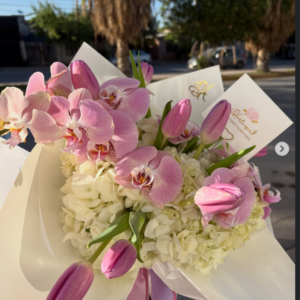 Ramo de orquídeas y tulipanes rosas con hortensias blancas, envuelto en papel marfil